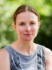 Headshot of Amy Newman taken outside with leaves in the background.