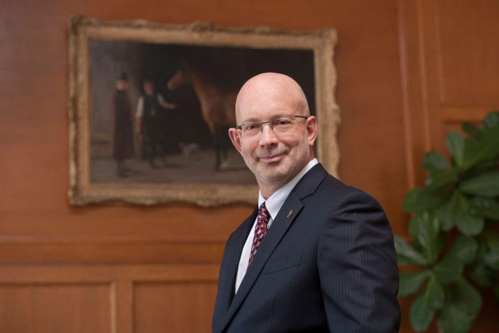 Photograph of Dr. Jeff Wichtel in a room with a large painting on the wall in the background.