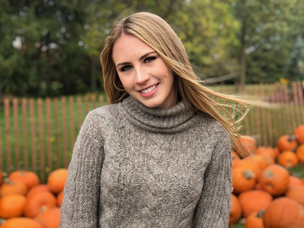 Headshot of Emily Robinson standing in front of pumpkins.