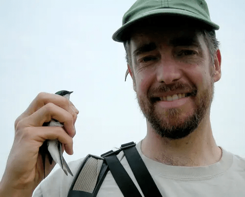 A headshot of Chris Earley holding a bird in his right hand.
