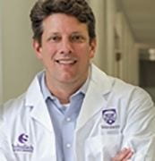 A headshot of Professor Eric Arts wearing a lab coat with a Western University logo on it

