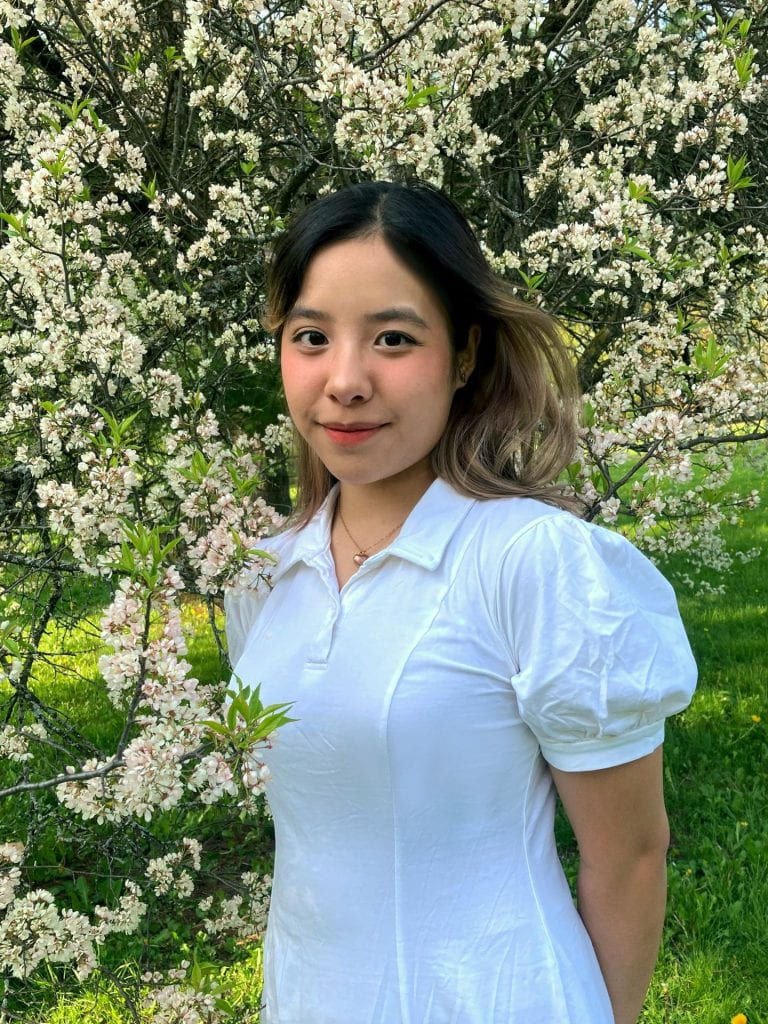 A portrait of Hanh Nguyen (Ava) Vu with flowers in the background