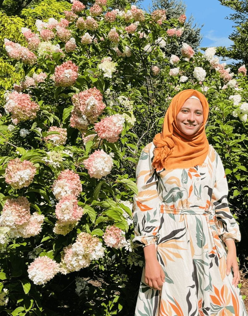 A portrait of Maryam Alhamdan with flowers in the background