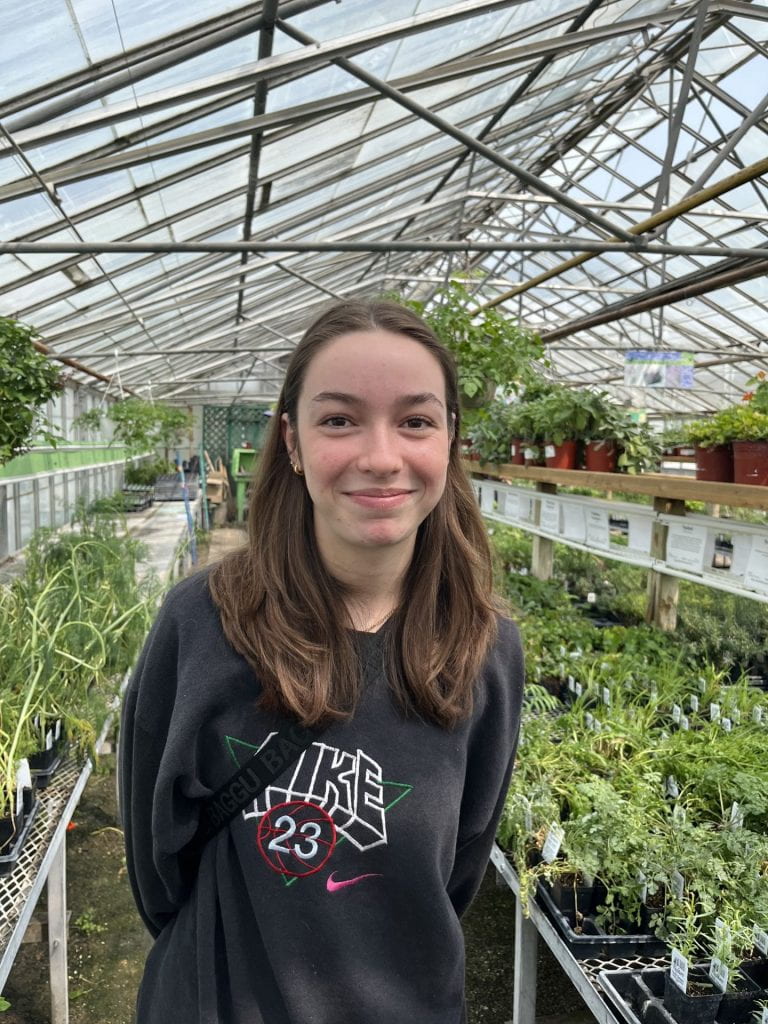 A photo of Maia in front of plants